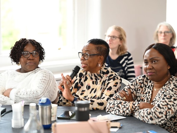 Members at a conference sitting at a table with one speaking from a remote mic